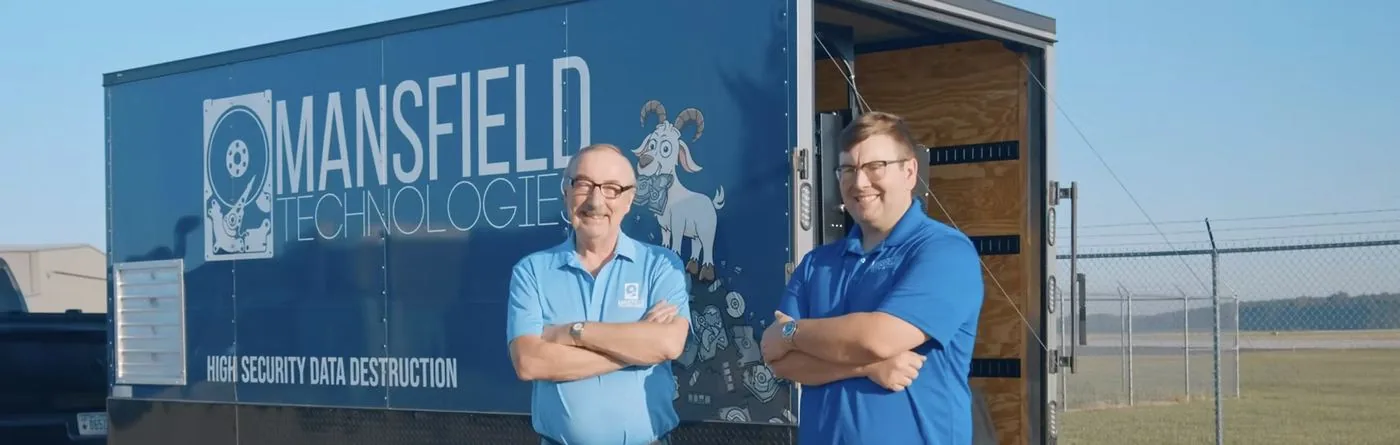 The mobile destruction trailer with its door open, Dan and Chris McDevitt in front of it