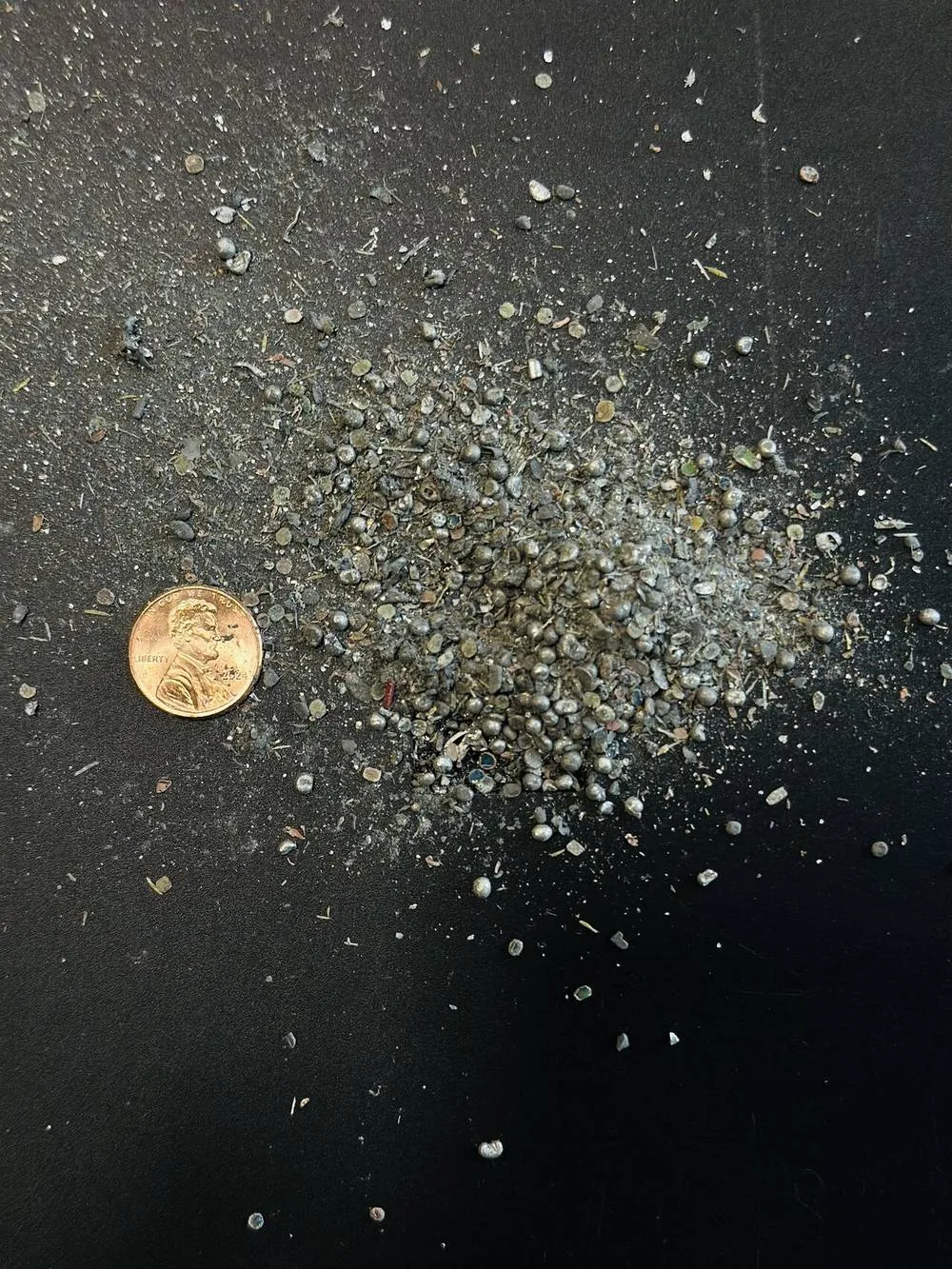 A small pile of metallic particles beside a penny